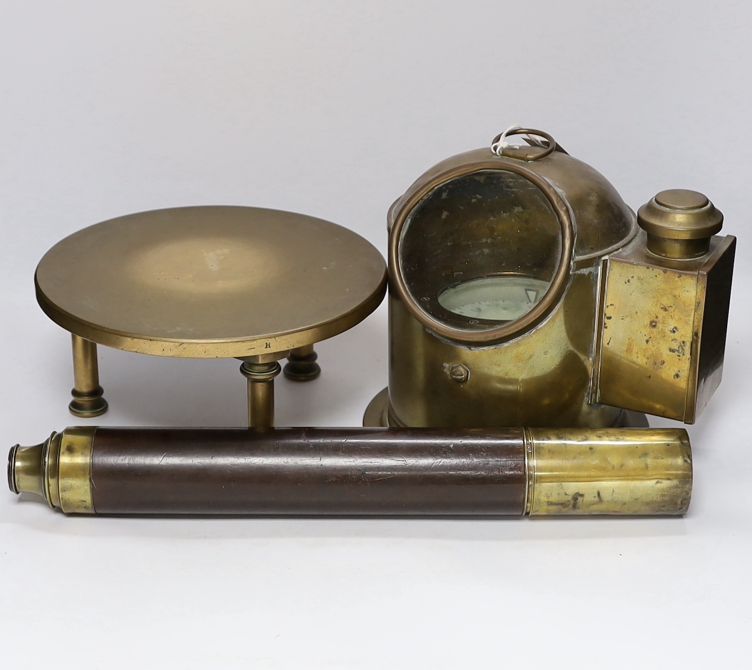 A ship’s brass binnacle containing a Sestrel compass and with a built in oil lamp, a bronze circular stand and a single draw telescope, binnacle 23cm high